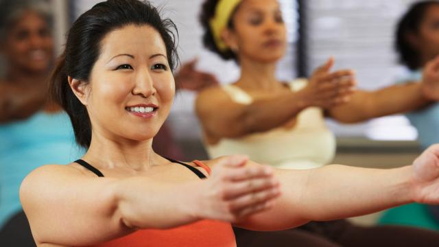 A group of women participating in a yoga class, focusing on a stretching exercise.
